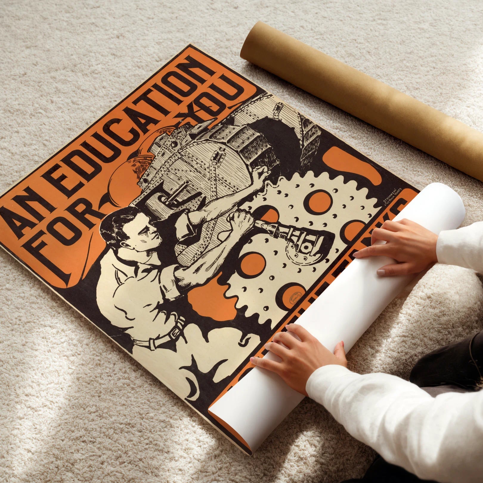 Person unrolling a large poster with mechanical design and text on a carpeted floor.
