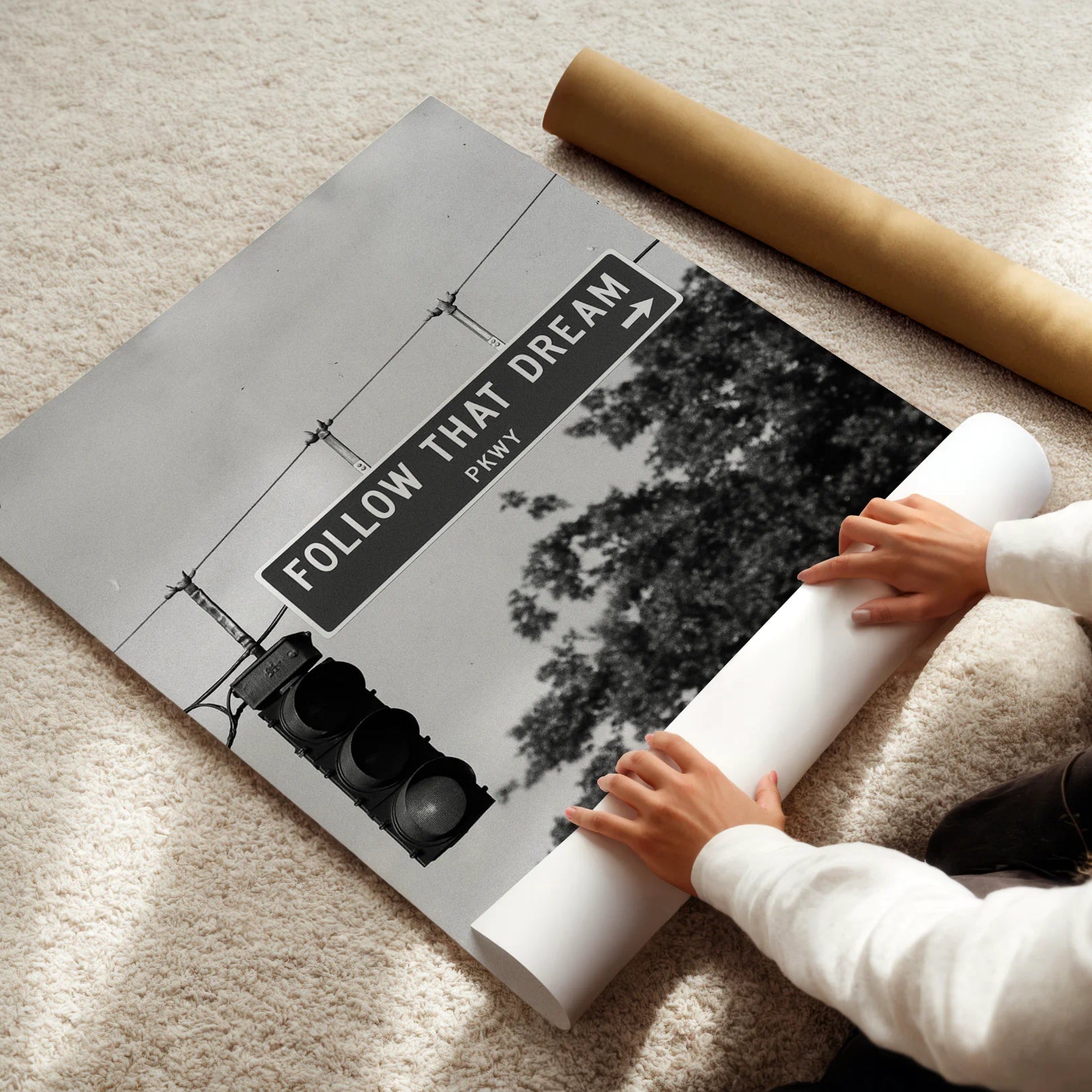 Person unrolling a large poster with 'Follow That Dream' text on a carpeted floor.