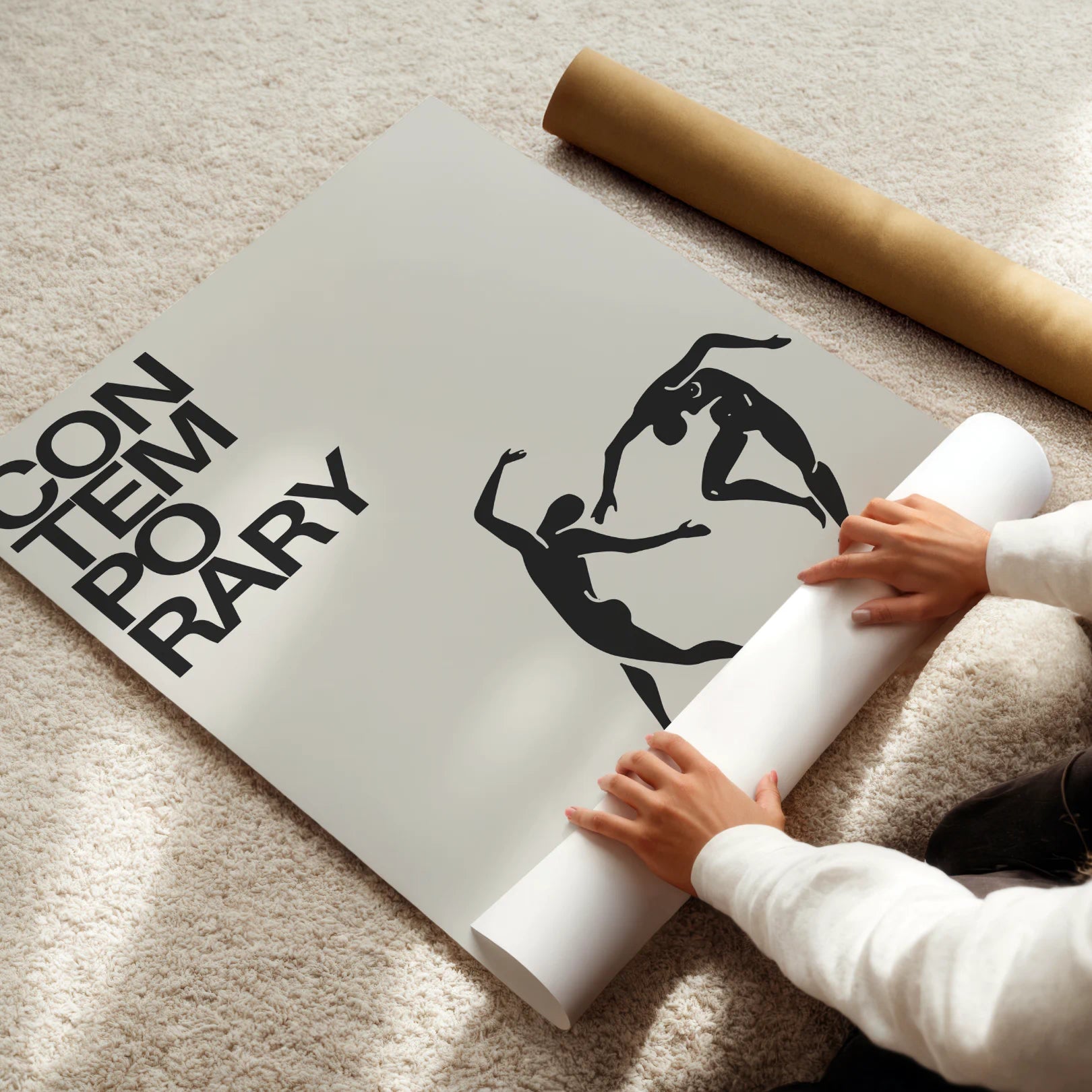 Person unrolling a large poster with artistic design on a light-colored floor.