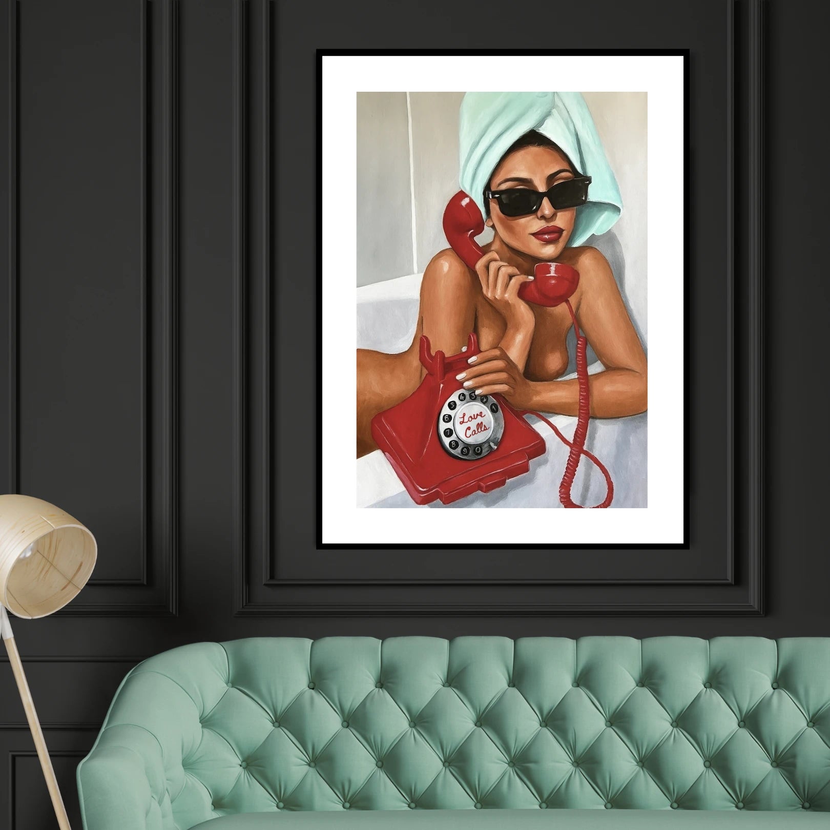 Framed artwork of a woman with a red phone on a black wall above a green sofa.