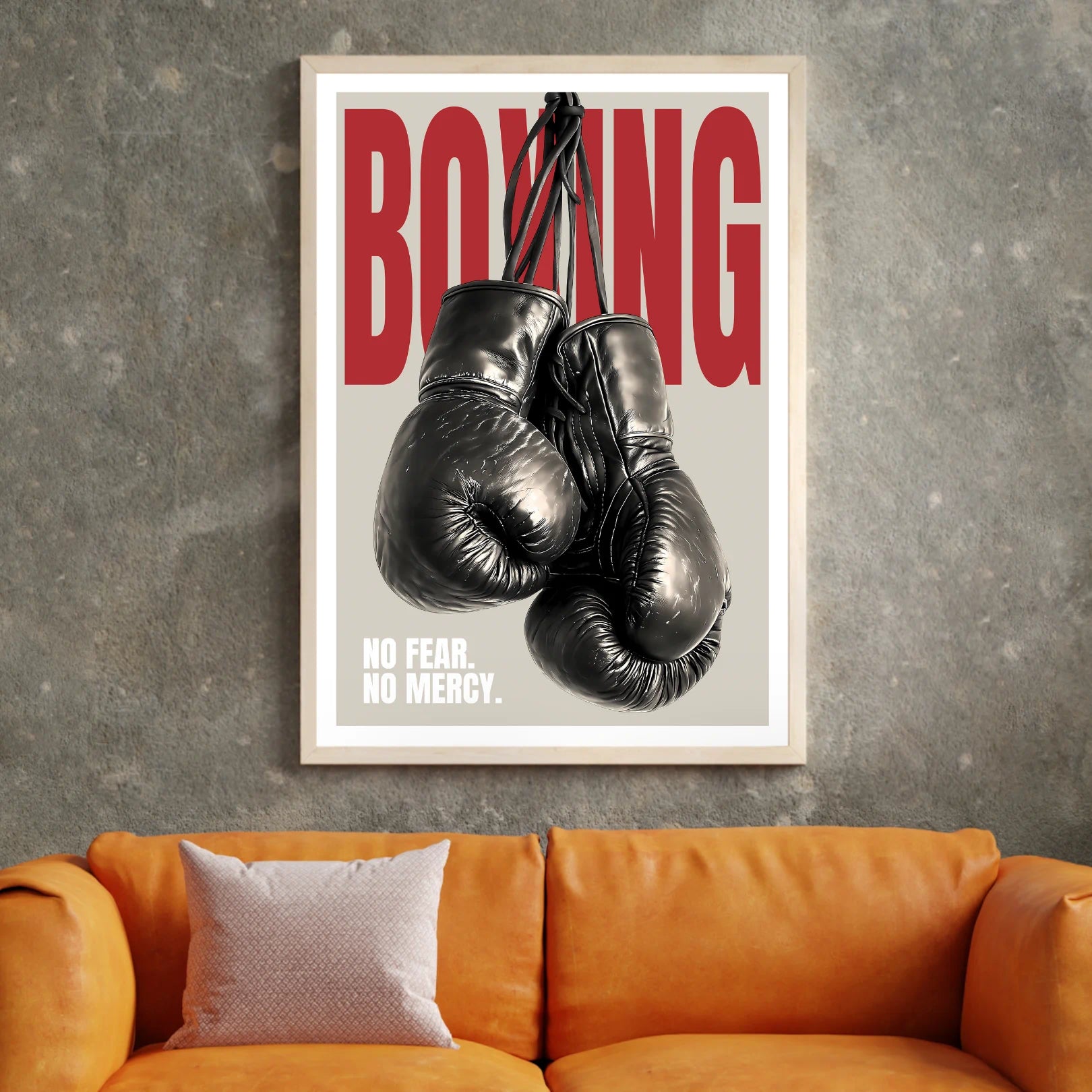 Framed poster with boxing gloves and 'BOXING NO FEAR. NO MERCY.' text on a gray wall above an orange couch.