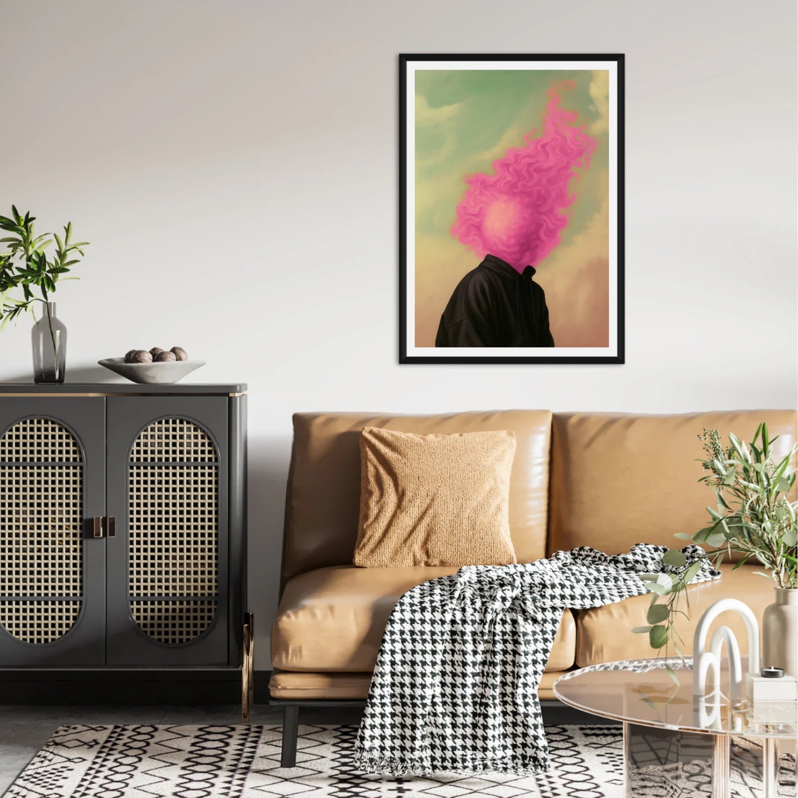 Poster of a mans head burning in pink flames in a Living room with a beige sofa, black cabinet, and colorful abstract art on the wall.