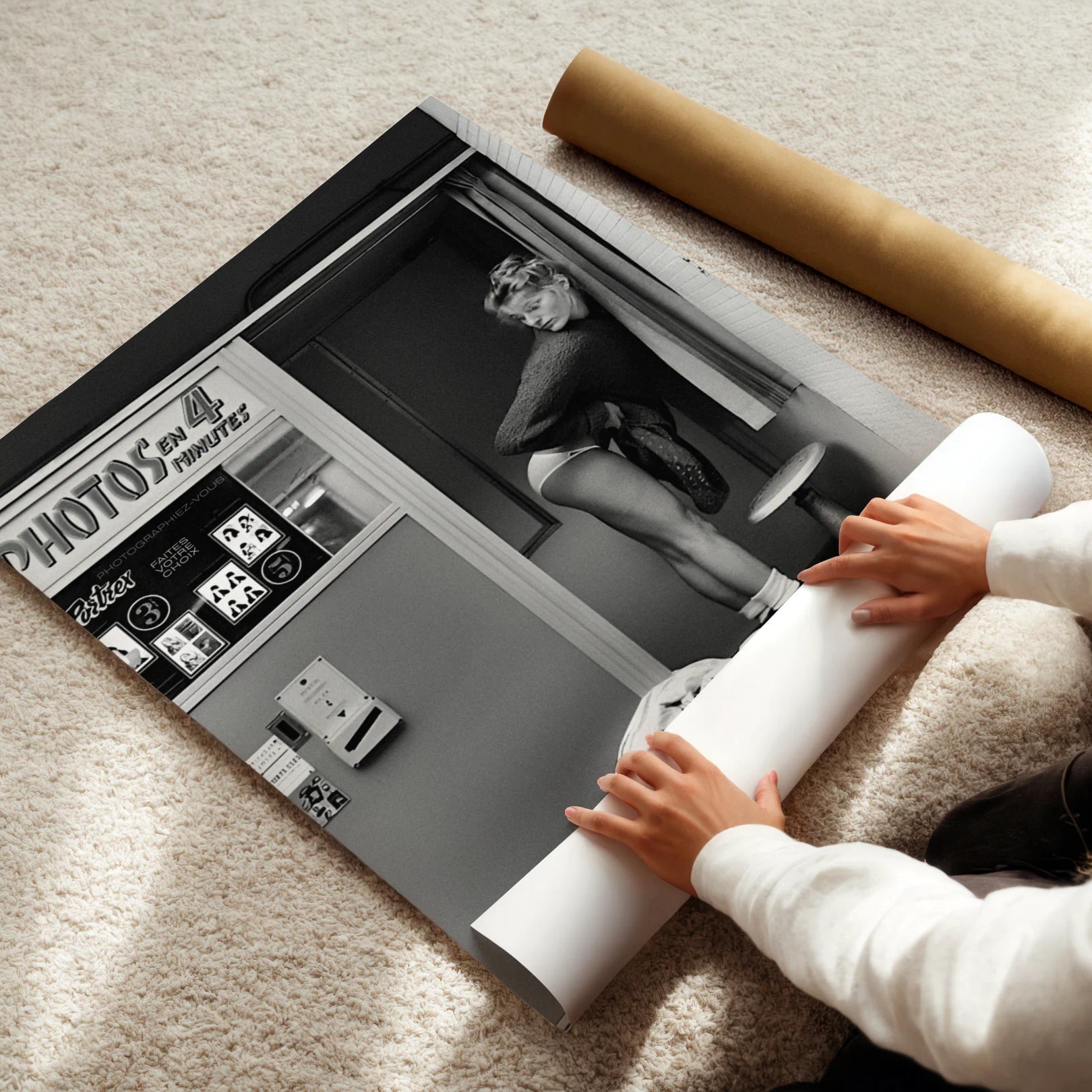 Person unrolling a large Photo Booth poster of a woman in underwear on a carpeted floor.