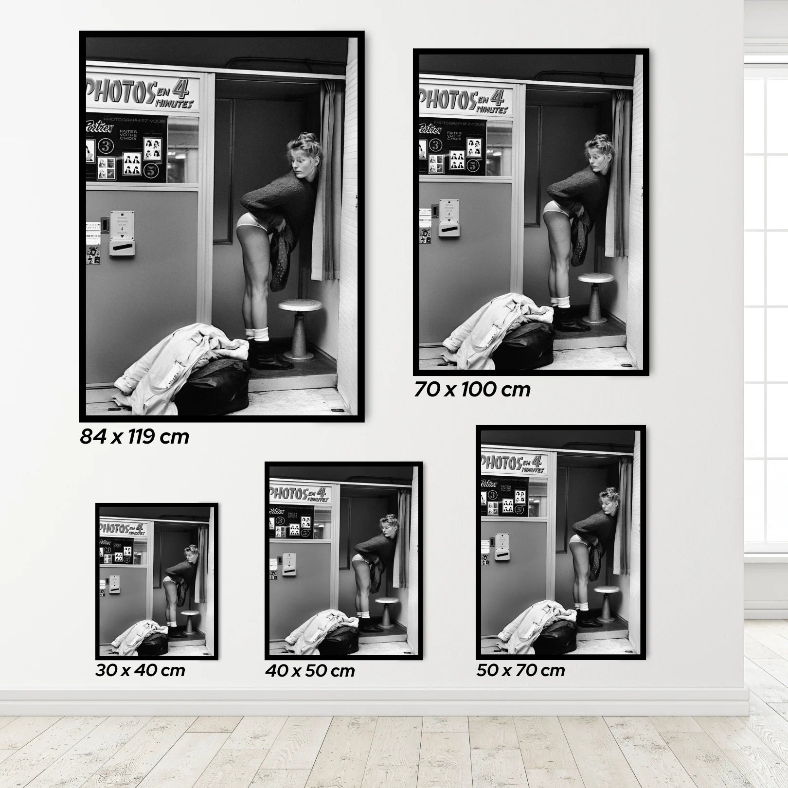 Set of a woman in a Photo Booth framed black and white posters on a wall with dimensions displayed.