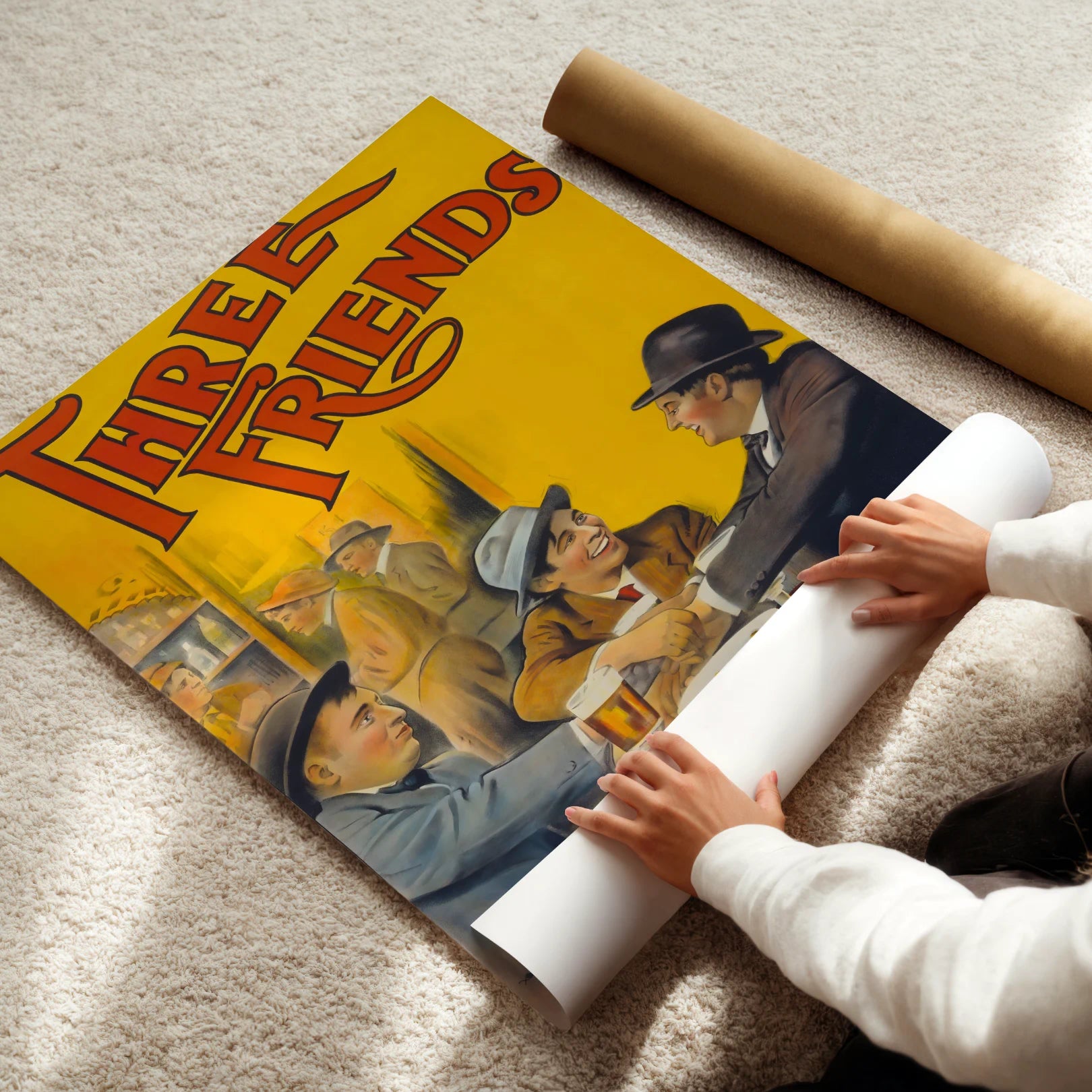 Person unrolling a poster of 'Three Men in a Boat' with a yellow background.