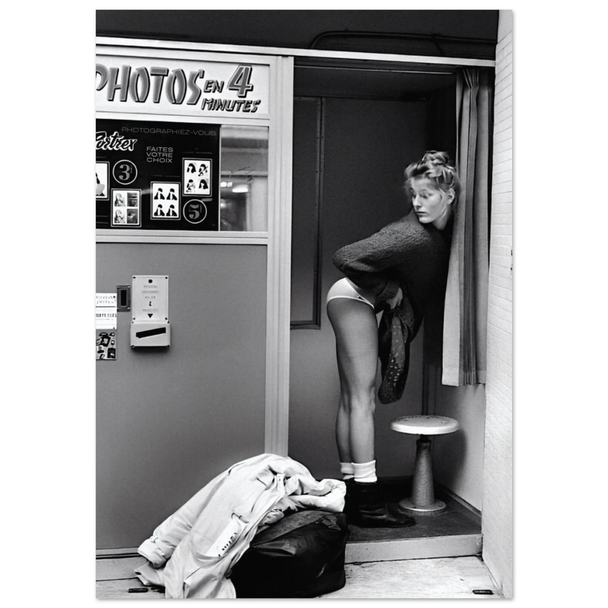Black and white photo of a woman in a photo booth with 'PHOTOS EN 4 MINUTES' sign.