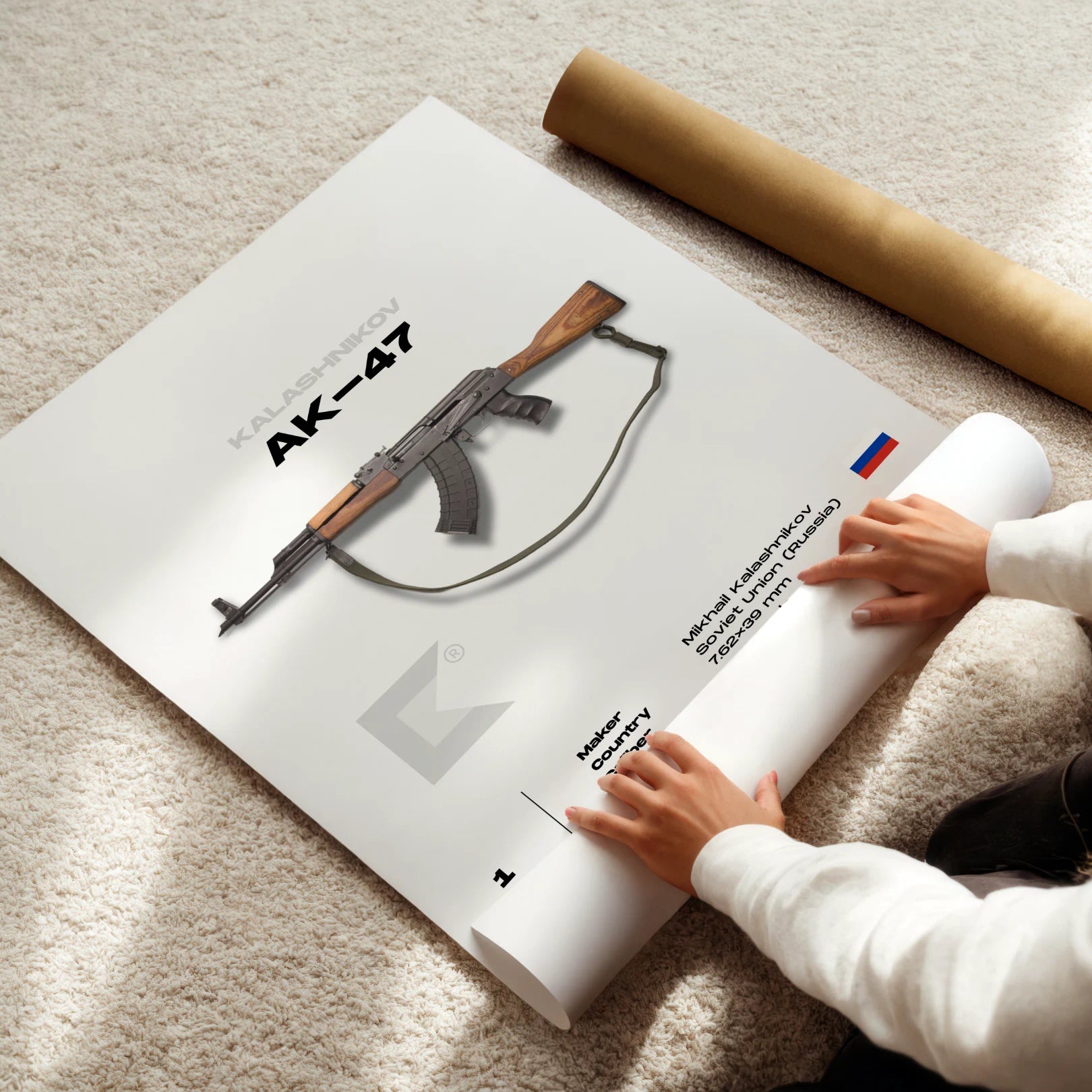 Person unrolling a poster of an AK-47 rifle on a carpeted floor.
