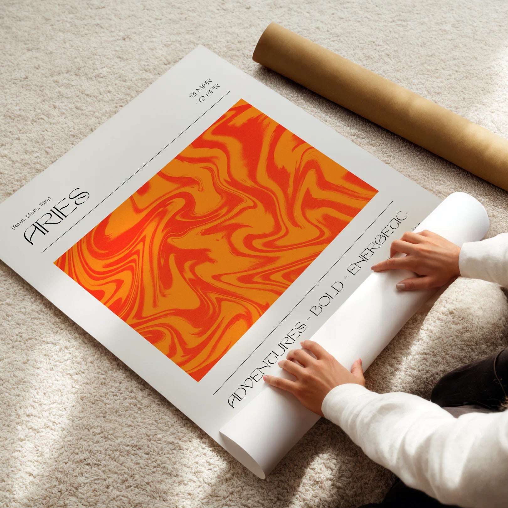 Person unrolling a large Aries poster with abstract design and text on a light carpet.