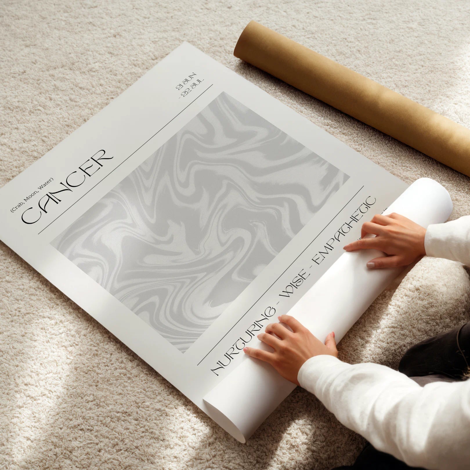 Person unrolling a large astrological poster titled 'Cancer' on a carpeted floor.