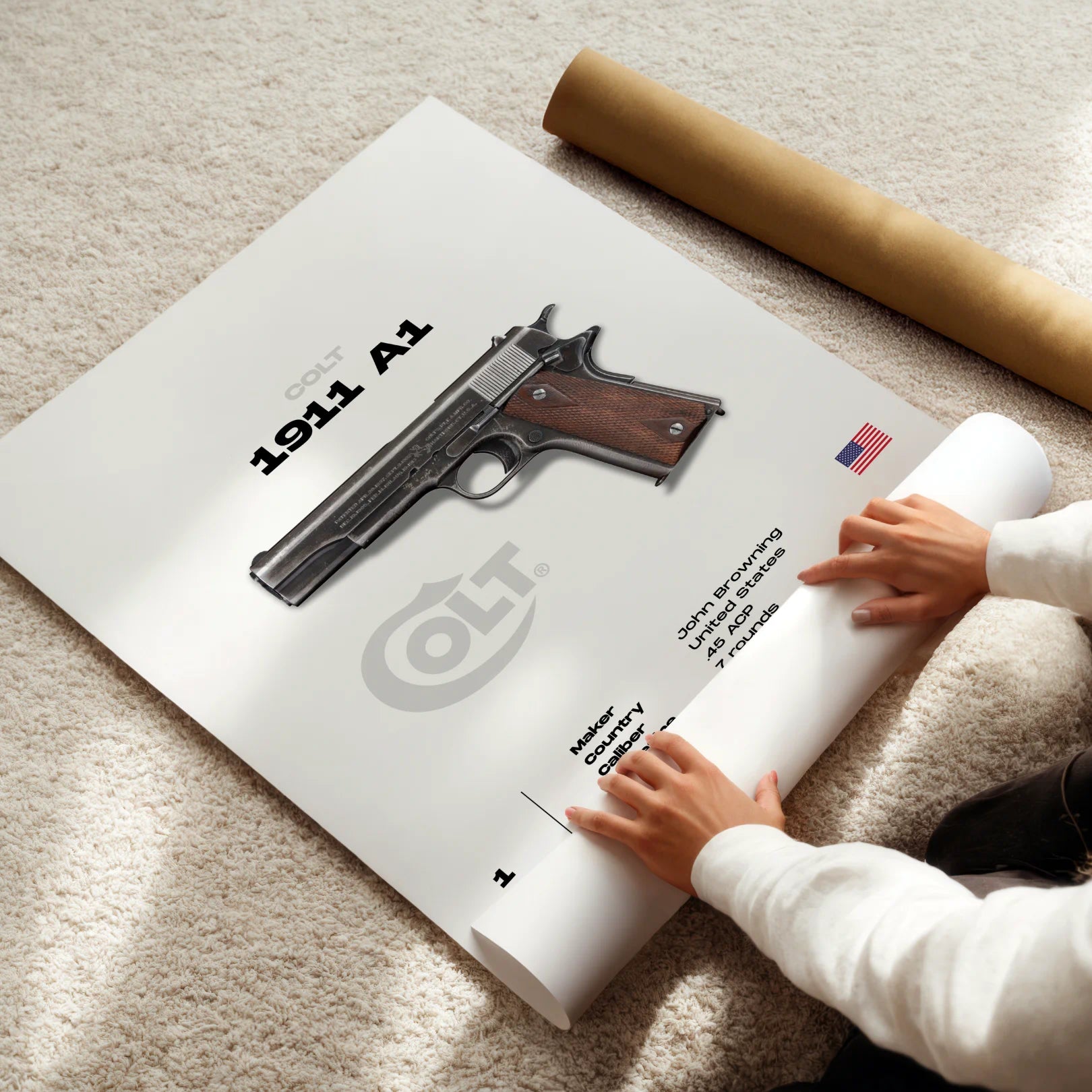 Person unrolling a poster of a 1911 A1 pistol on a carpeted floor.