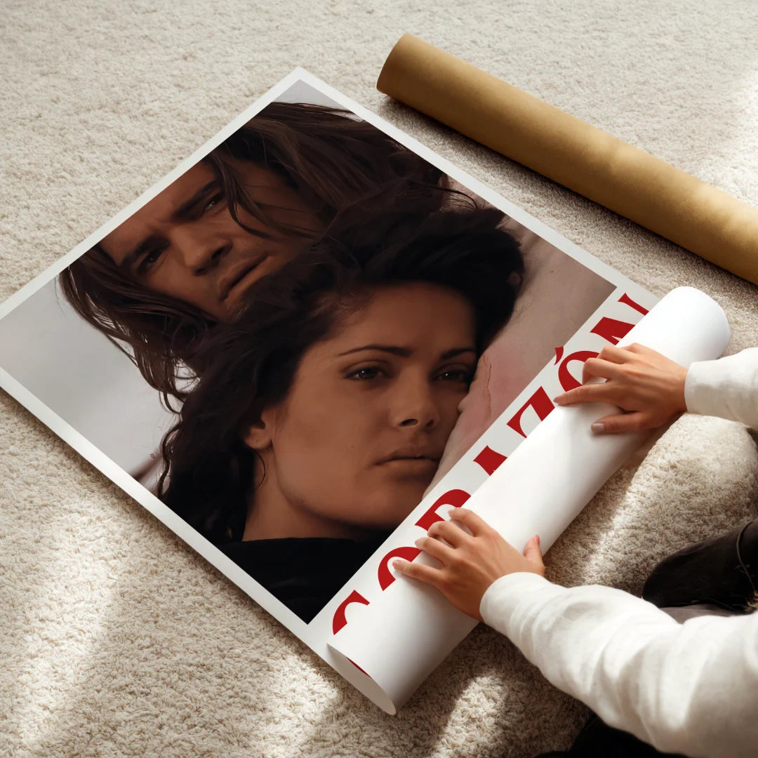 Person unrolling a large poster of Antonio Banderas and selma Hayek from the movie desperado on a carpeted floor.