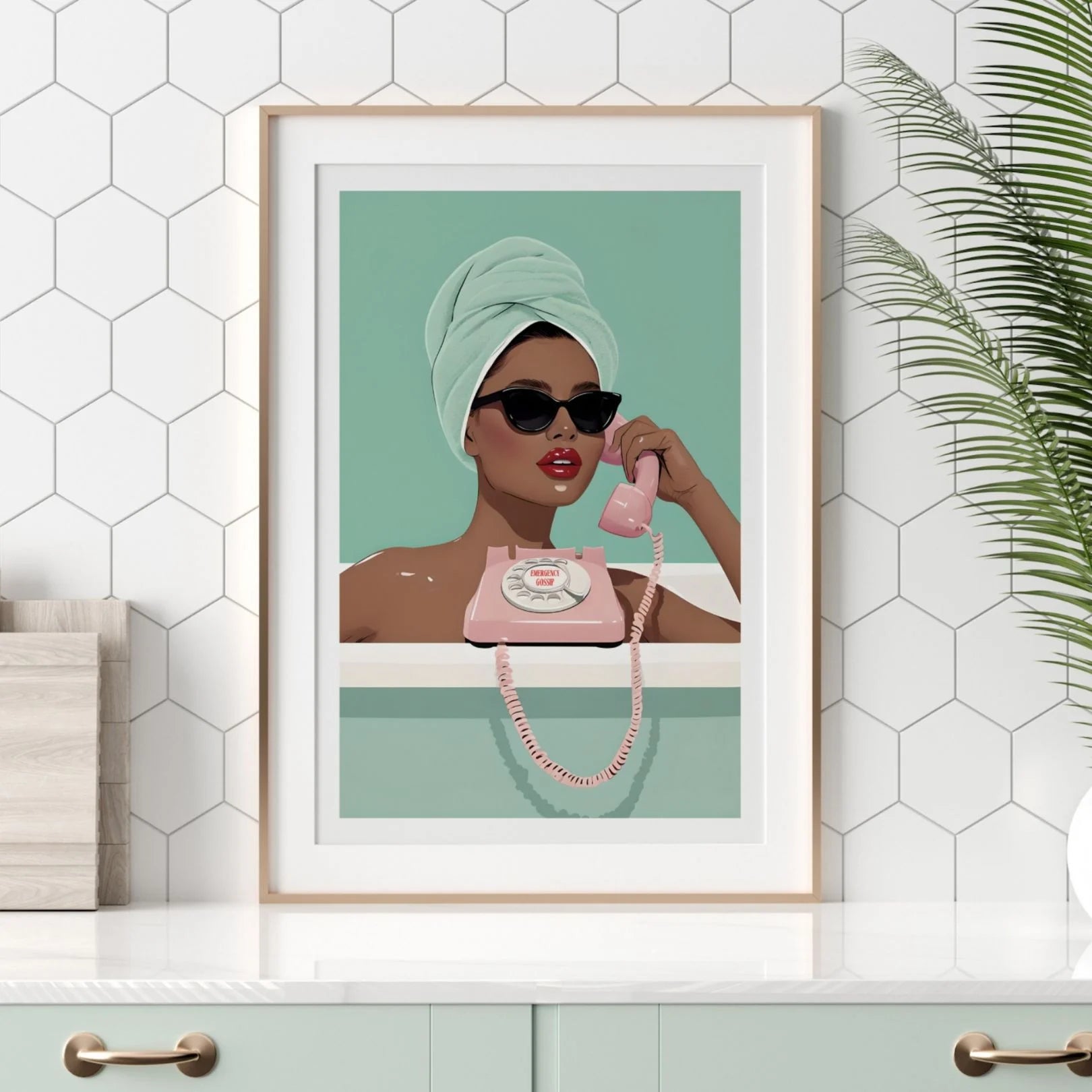 Emergency Gossip wall print with chic woman in bath, displayed in modern white-tiled kitchen with greenery