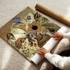 Person unrolling a decorative poster with floral and peacock feather design on a light-colored floor.