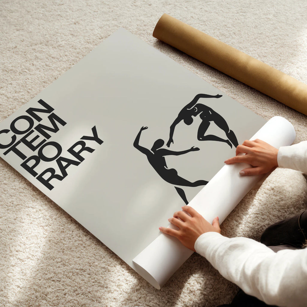 Person unrolling a large poster with artistic design on a light-colored floor.