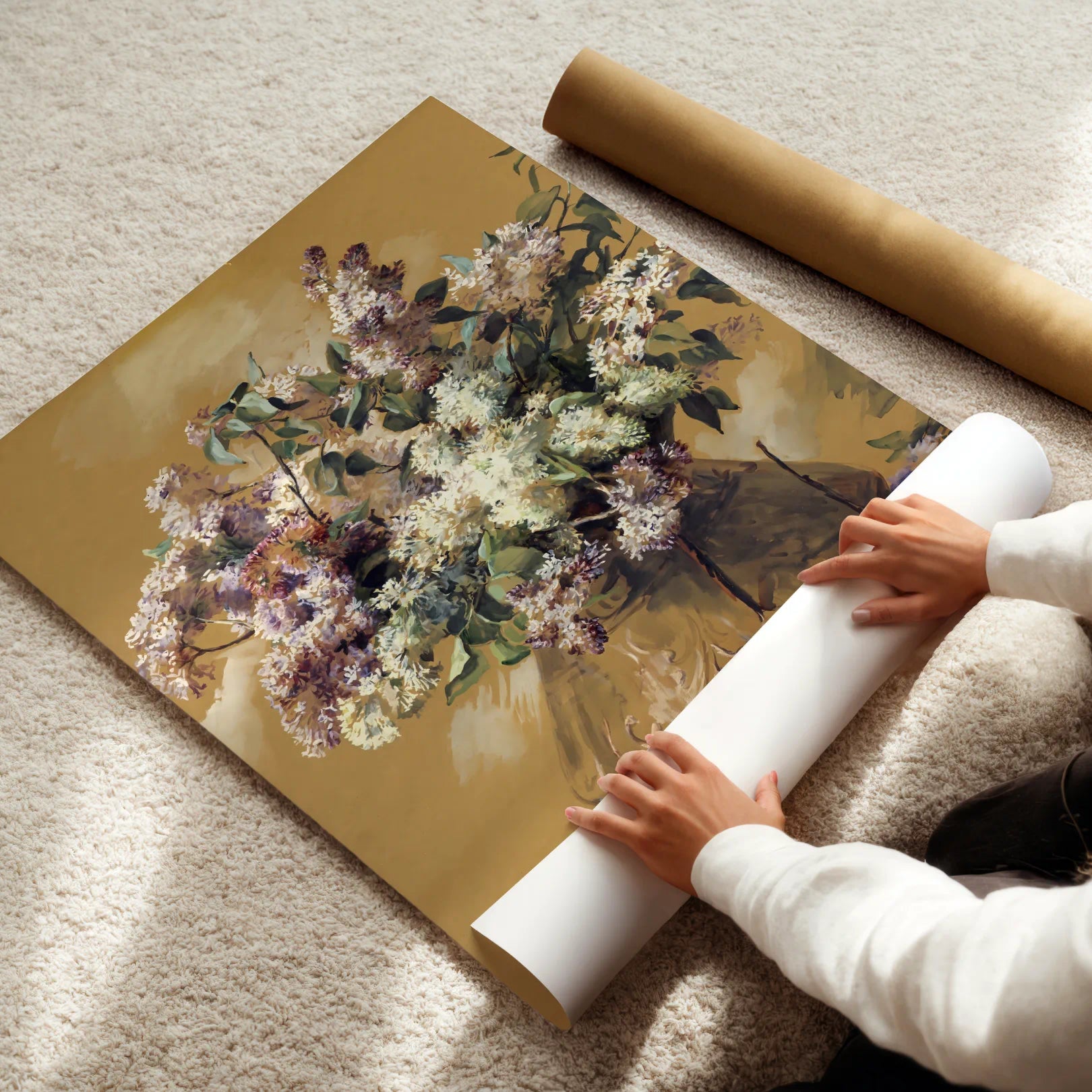Person unrolling a floral poster on a carpeted floor