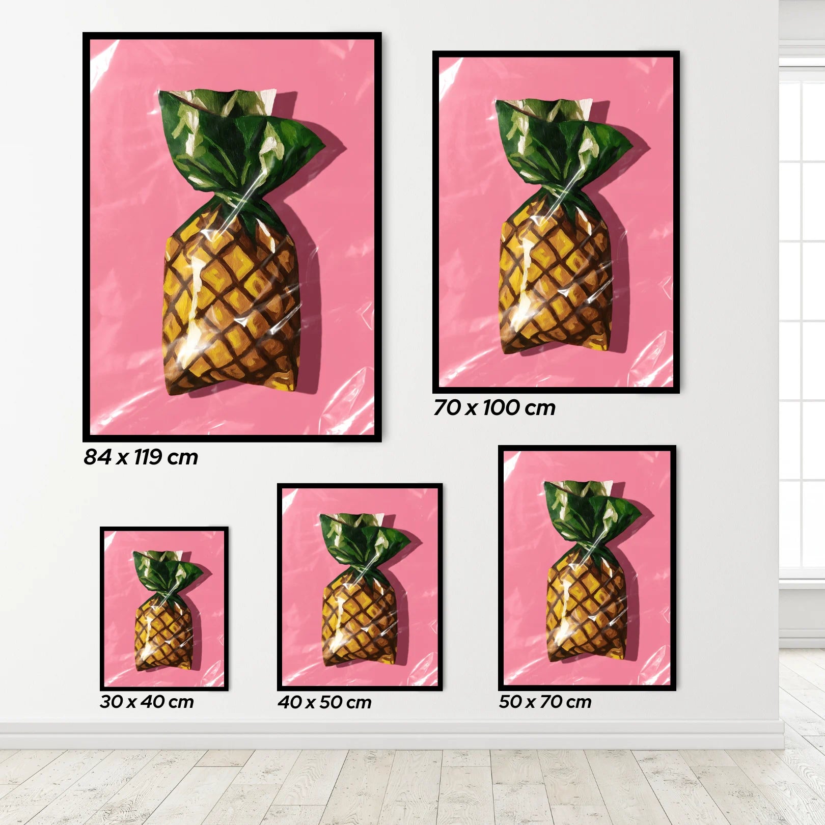 Set of framed pineapple wall art with different sizes on a pink background.