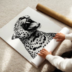 Person unrolling a large black and white leopard print poster on a light-colored floor.