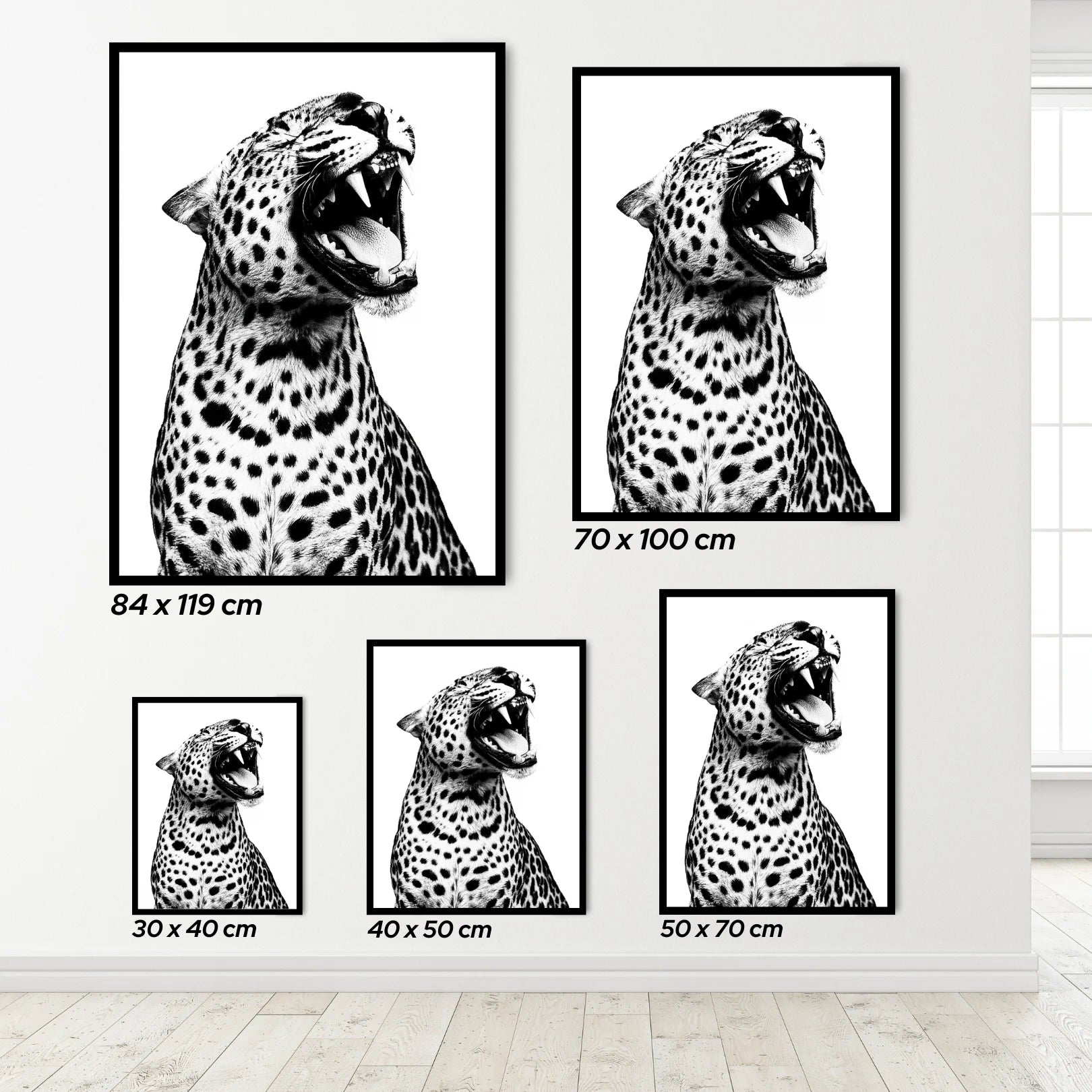 Set of black and white leopard prints of different sizes on a light gray wall.