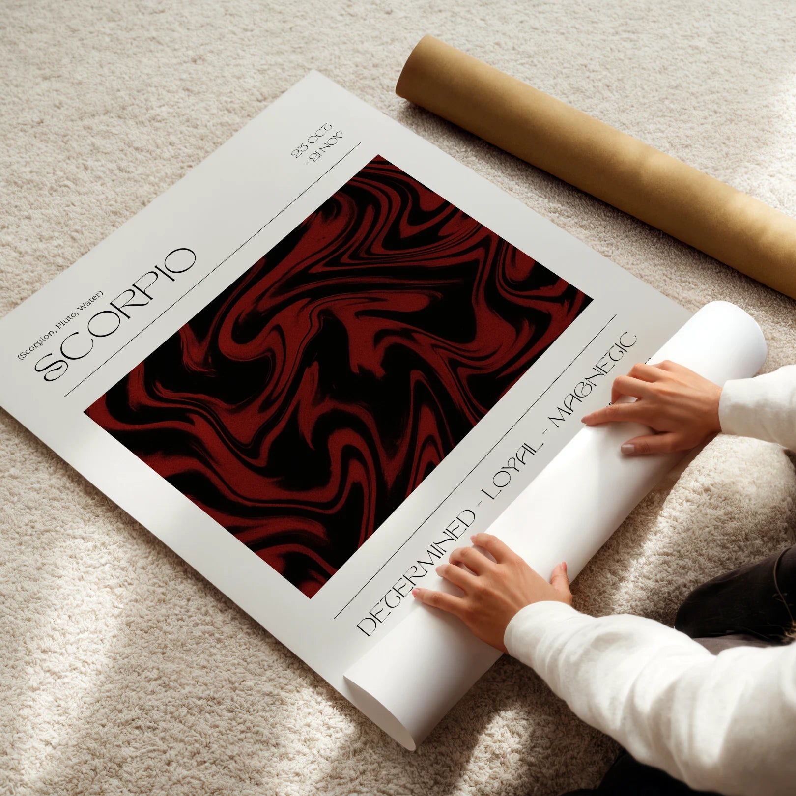 Person unrolling a Scorpio zodiac poster with a marbled design on a light surface.