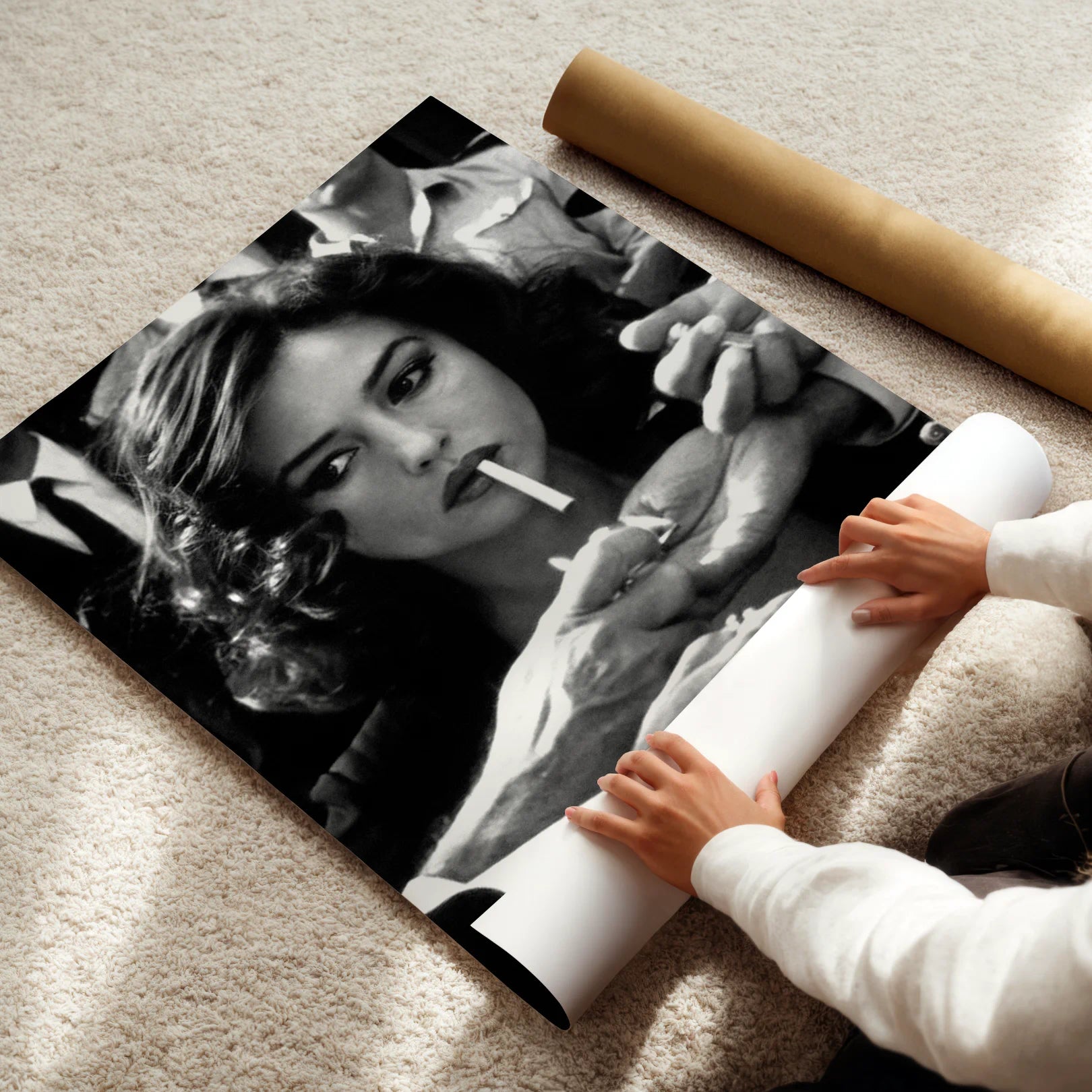 Person unrolling a large black and white poster of Malena movie actor on a carpeted floor.