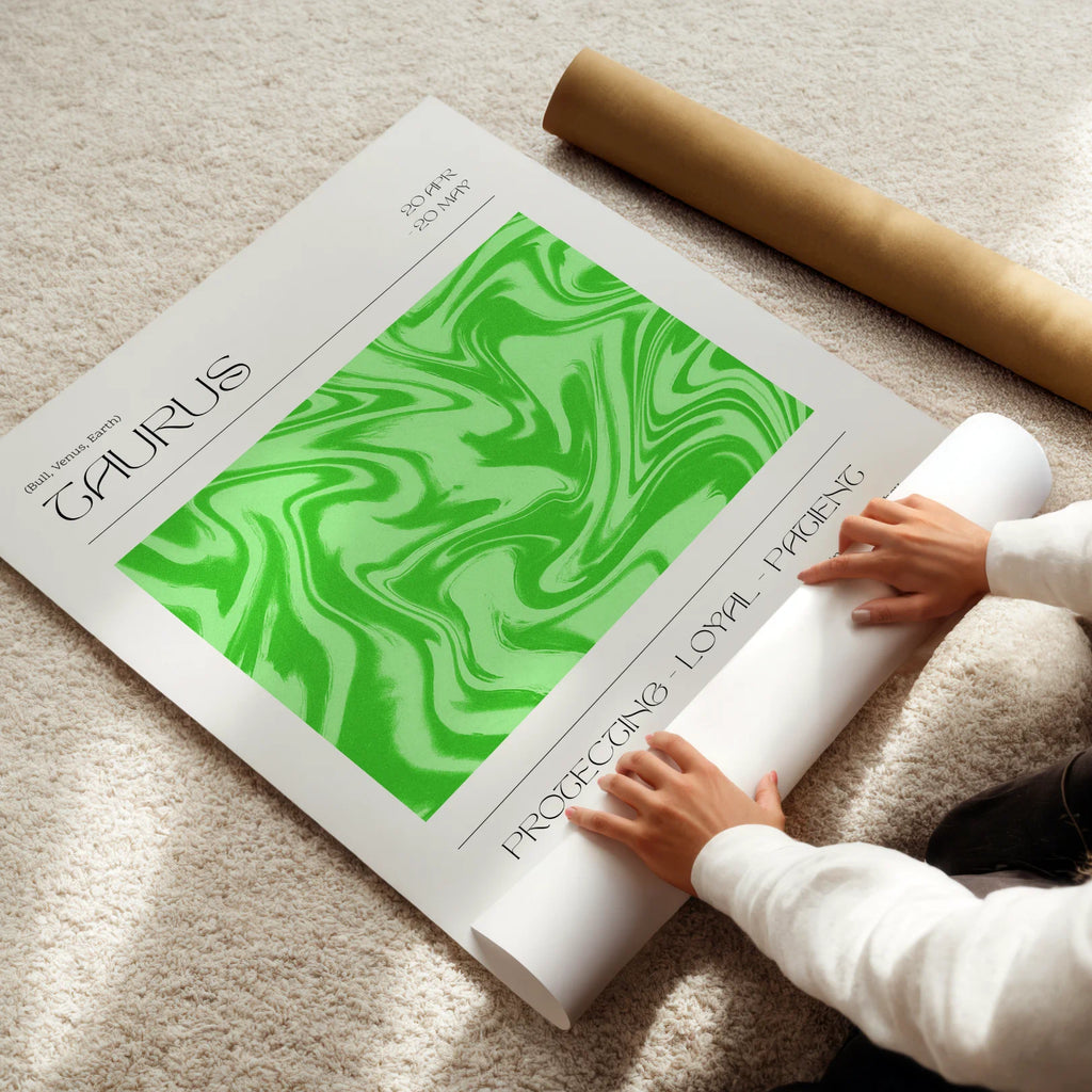 Person unrolling a green and white taurus astrological poster on a light-colored floor.
