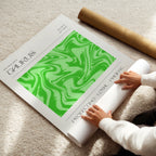 Person unrolling a green and white taurus astrological poster on a light-colored floor.