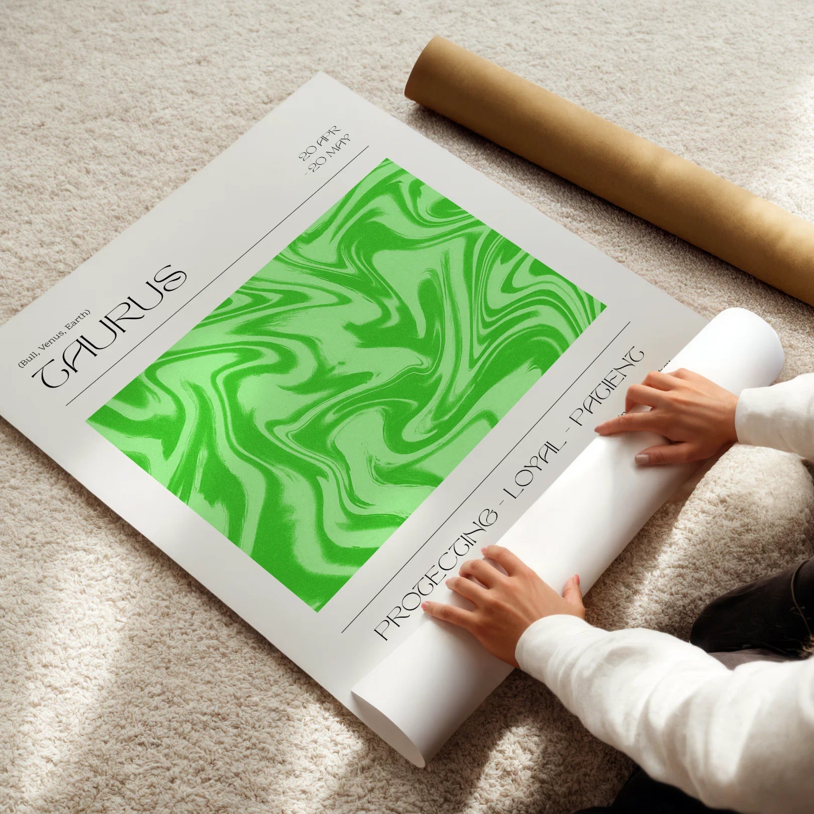 Person unrolling a green and white taurus astrological poster on a light-colored floor.